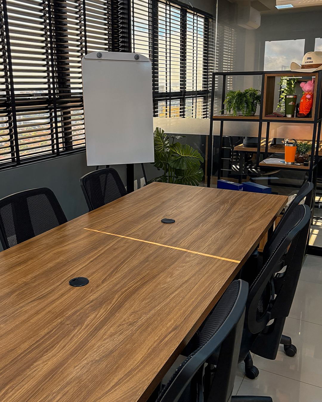 Sala de reunião com mesa de madeira e flip chart